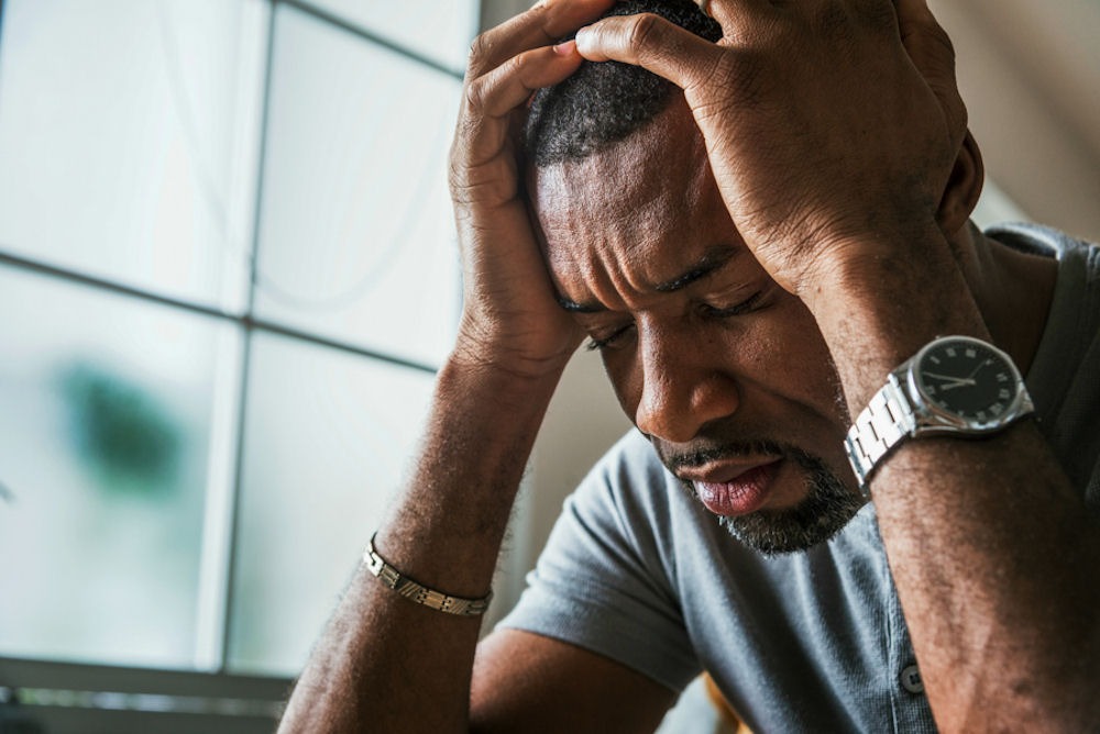 a man holding his head showing signs suffering from mental health