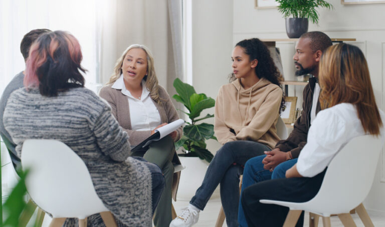 Counseling, group and psychology discussion with group of diversity people in therapy for depression, stress and anxiety. Men and women healing during psychologist meeting talking about mental health group with therapist discussing residential ptsd treatment program